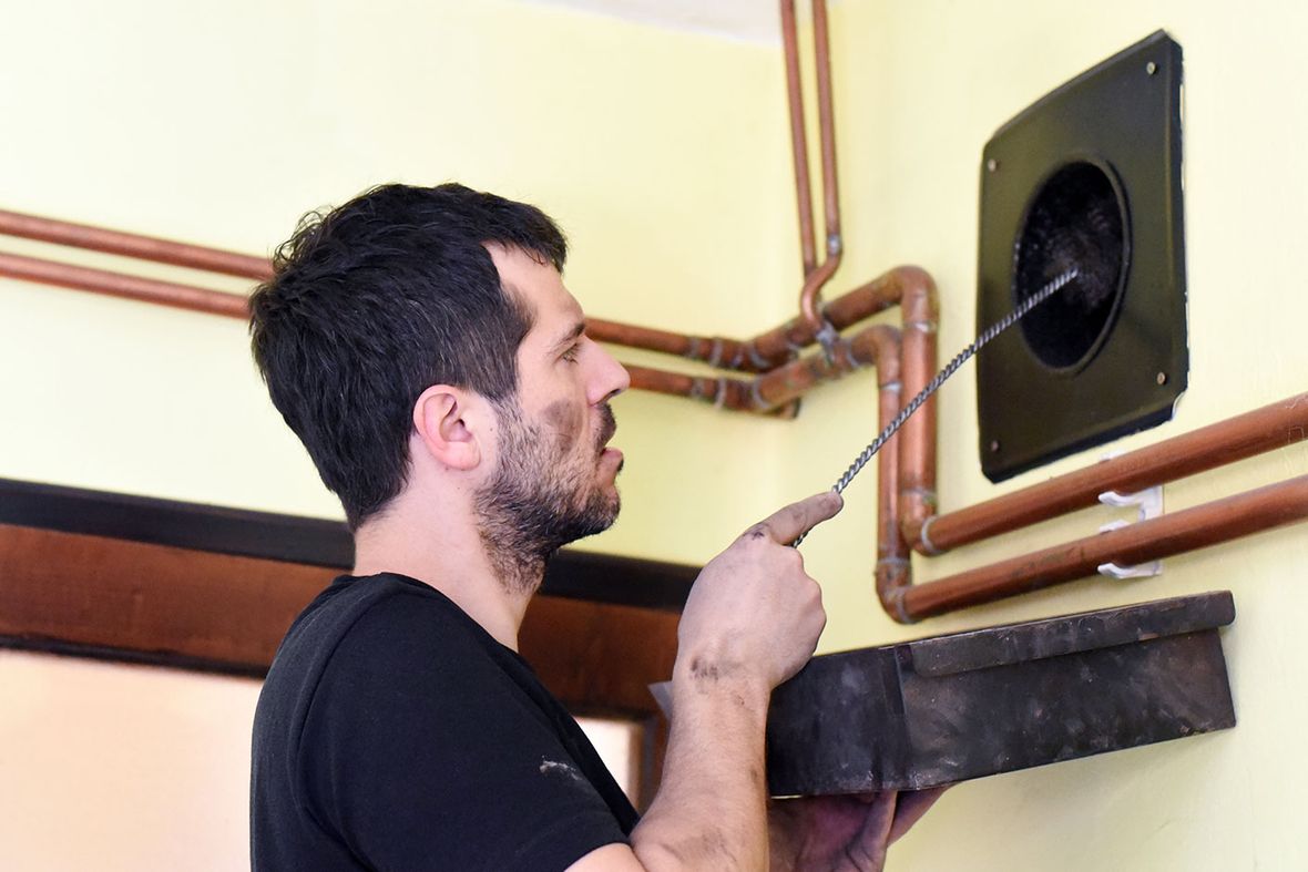 A chimney sweep cleaning out a vent